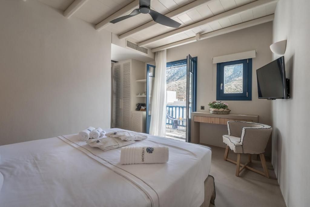 Helles Hotelzimmer mit Doppelbett, Deckenventilator und Blick durch die Balkontür