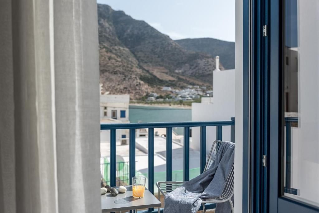Blick von einem Balkon mit blauem Geländer auf das Meer und die Berge.