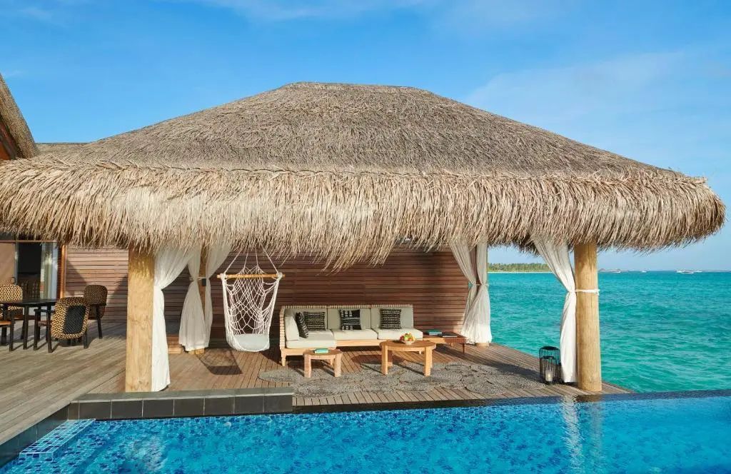 Privater Pool auf einer Holzterrasse direkt über dem türkisfarbenen Meer.