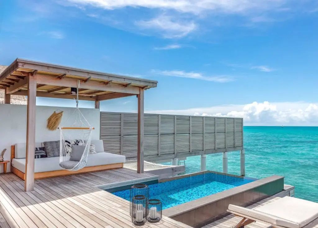 Sonnendeck mit privatem Pool, Loungemöbeln und Holzverkleidung am Meer.