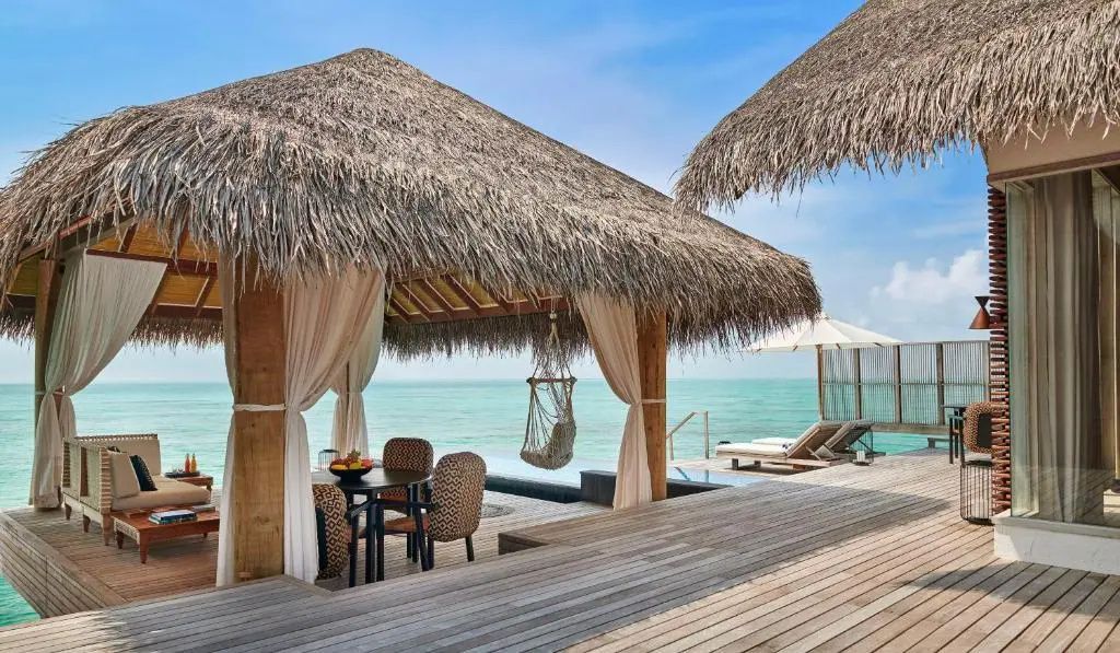 Überdachte Holzterrasse mit Sitzgelegenheiten, Hängesessel und Blick aufs Meer.