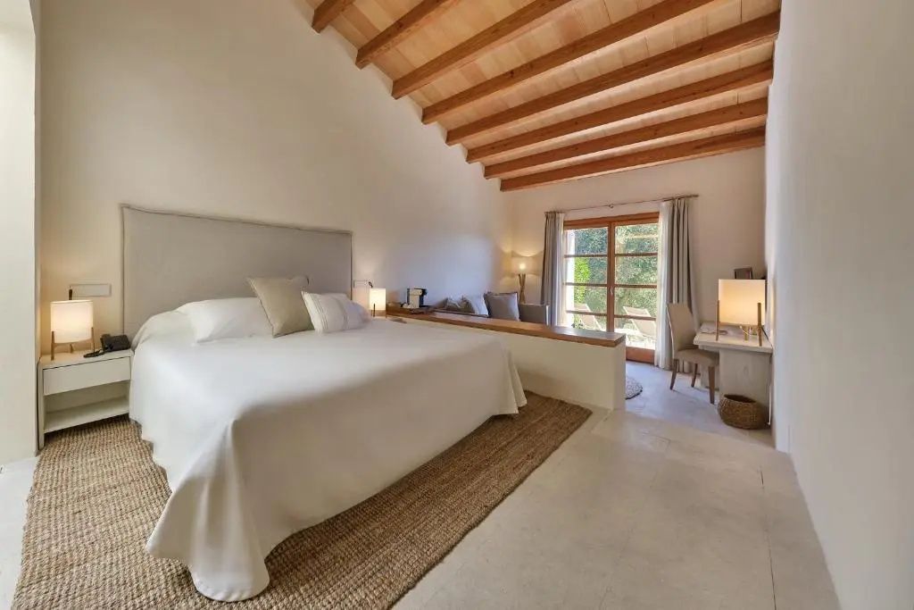 Schlafzimmer mit großem Doppelbett, Holzbalkendecke und Zugang zum Sitzbereich.
