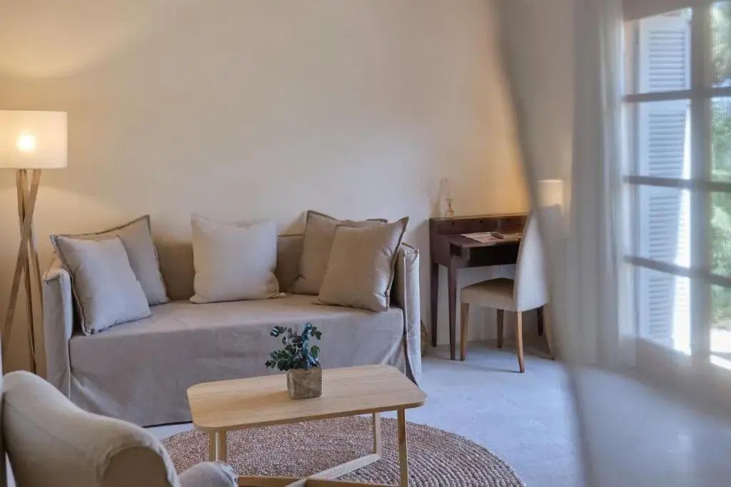Heller Sitzbereich im Zimmer mit beigem Sofa und Holztisch auf Rundteppich.