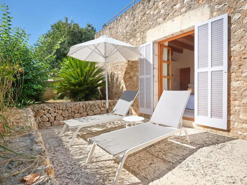 Terrasse aus Naturstein mit zwei Sonnenliegen, Sonnenschirm und Zugang zum Hotelzimmer