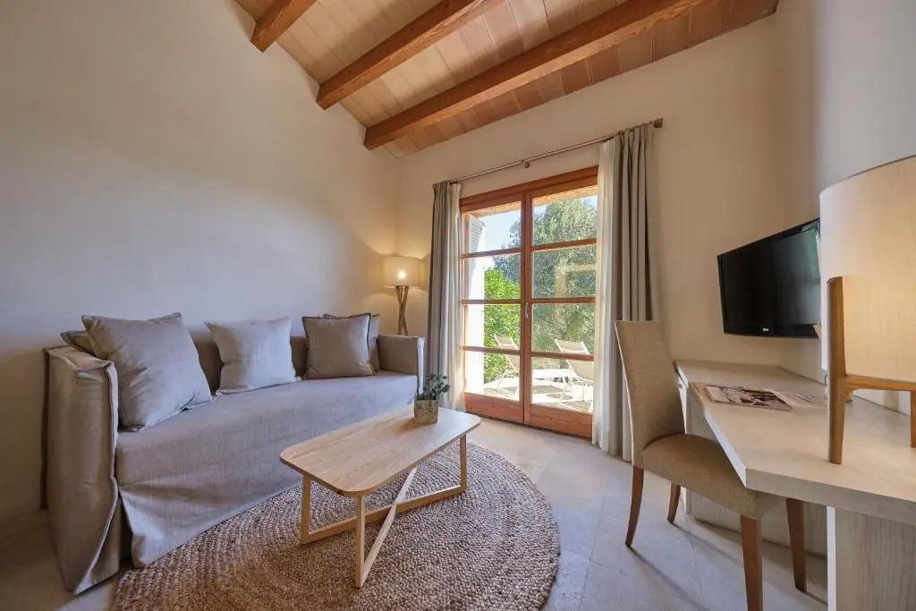 Heller Wohnraum mit Sofa, Schreibtisch und großer Glastür mit Blick nach draußen.