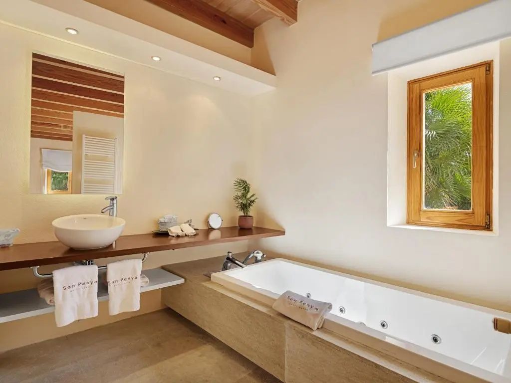 Badezimmer mit weißer Badewanne, Aufsatzwaschbecken, Holzablage und Tageslichtfenster