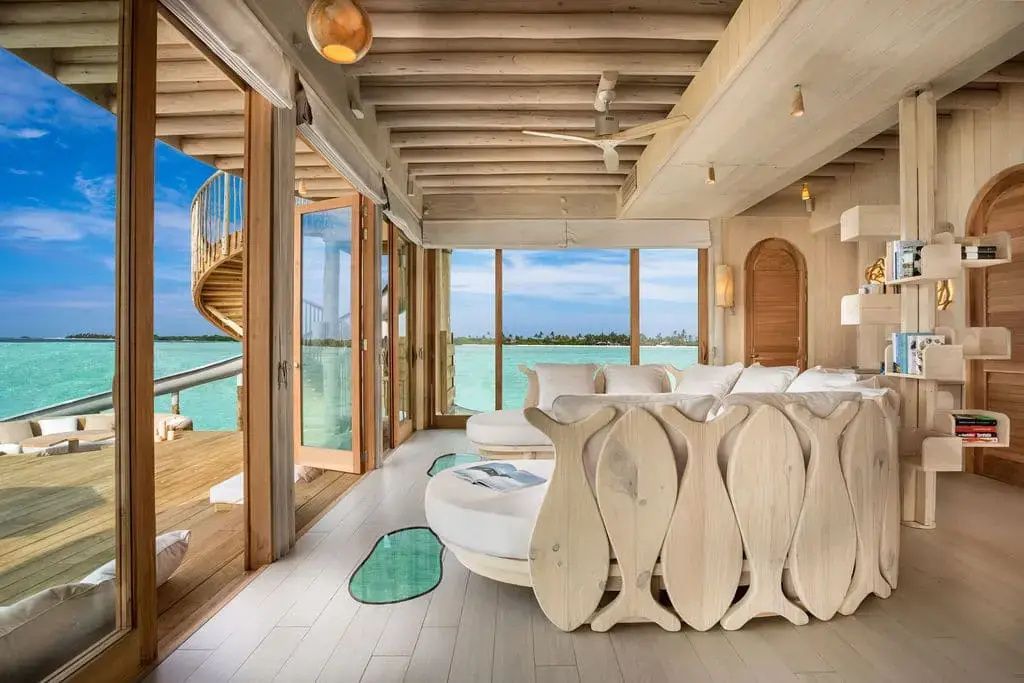 Heller Wohnraum aus Holz mit fischförmigen Rückenlehnen und Blick auf die Lagune.