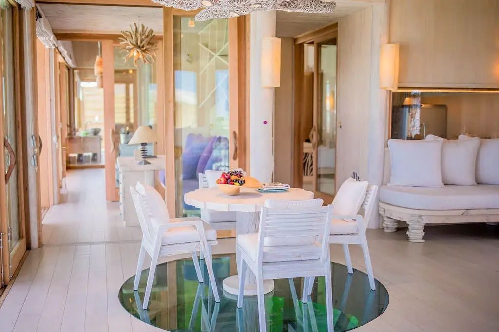 Weißer Esstisch mit Stühlen auf einem Glaseinsatz im Holzfußboden einer Villa.