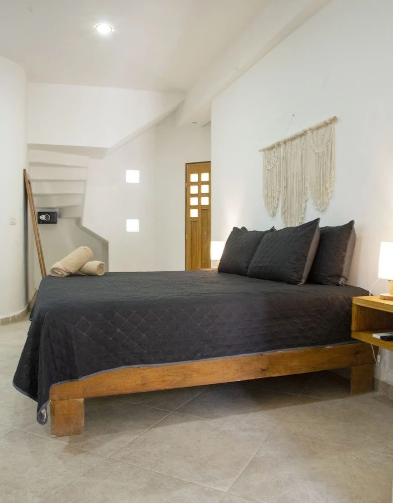 Schlafbereich mit Holzdoppelbett und Wanddekoration aus Makramee sowie Treppe.