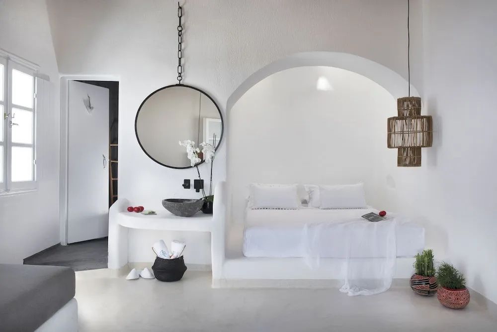 Ein weißes Zimmer mit integriertem Bett in einer Wandnische und angrenzendem Waschtisch.