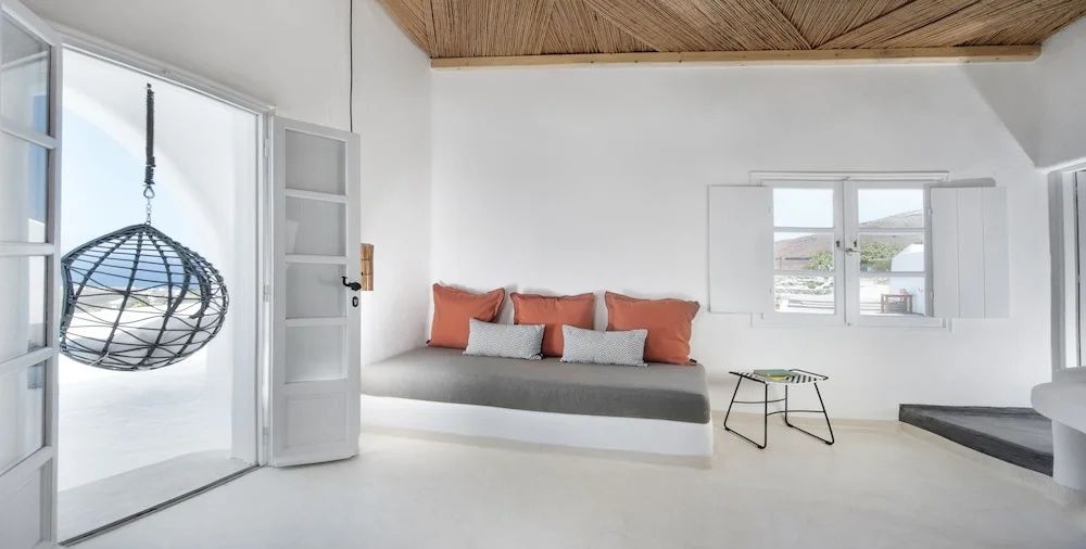 Sitzbereich mit fest eingebauter Bank, Kissen in Terrakotta und Grau sowie weißer Wand.