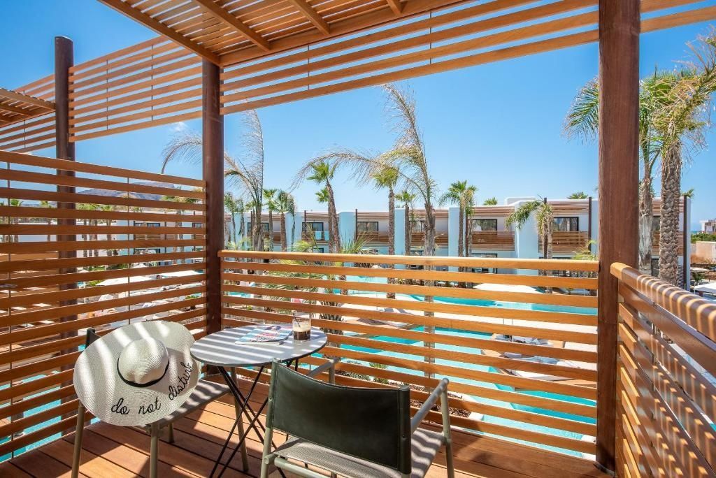 Balkon mit Holzlamellen, rundem Tisch und Stuhl mit Blick auf den Poolbereich.