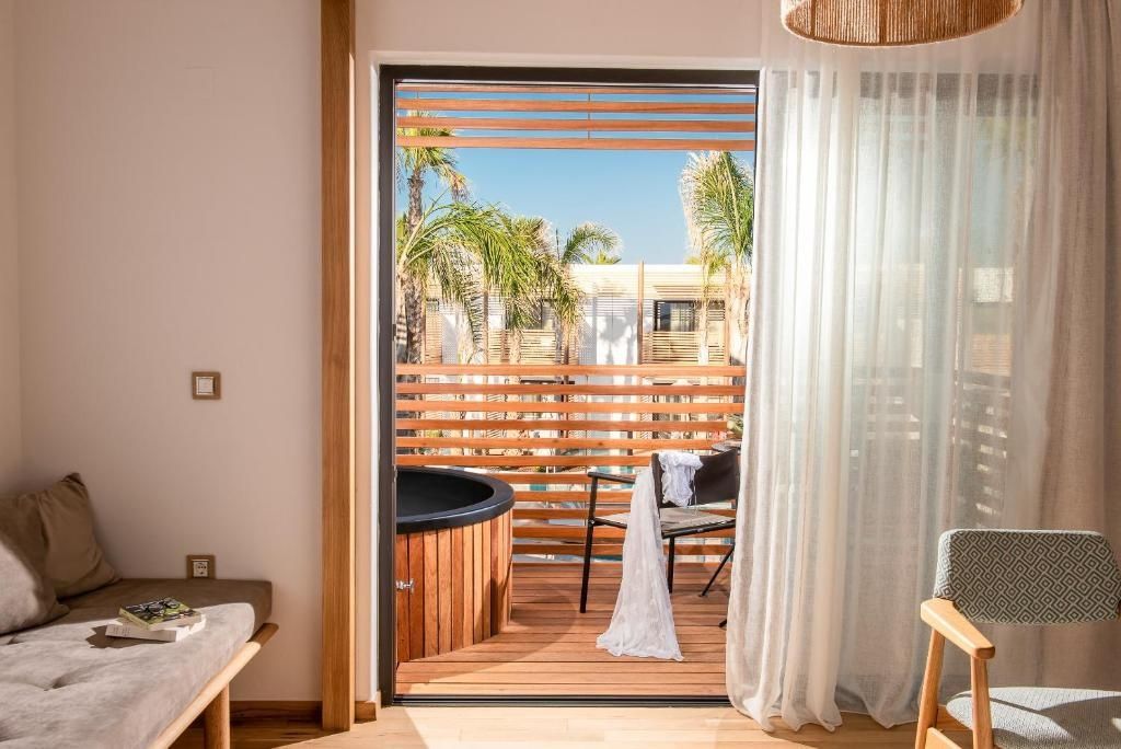 Balkon mit Whirlpool aus Holz, Stuhl und Blick auf Palmen und die Resortanlage.
