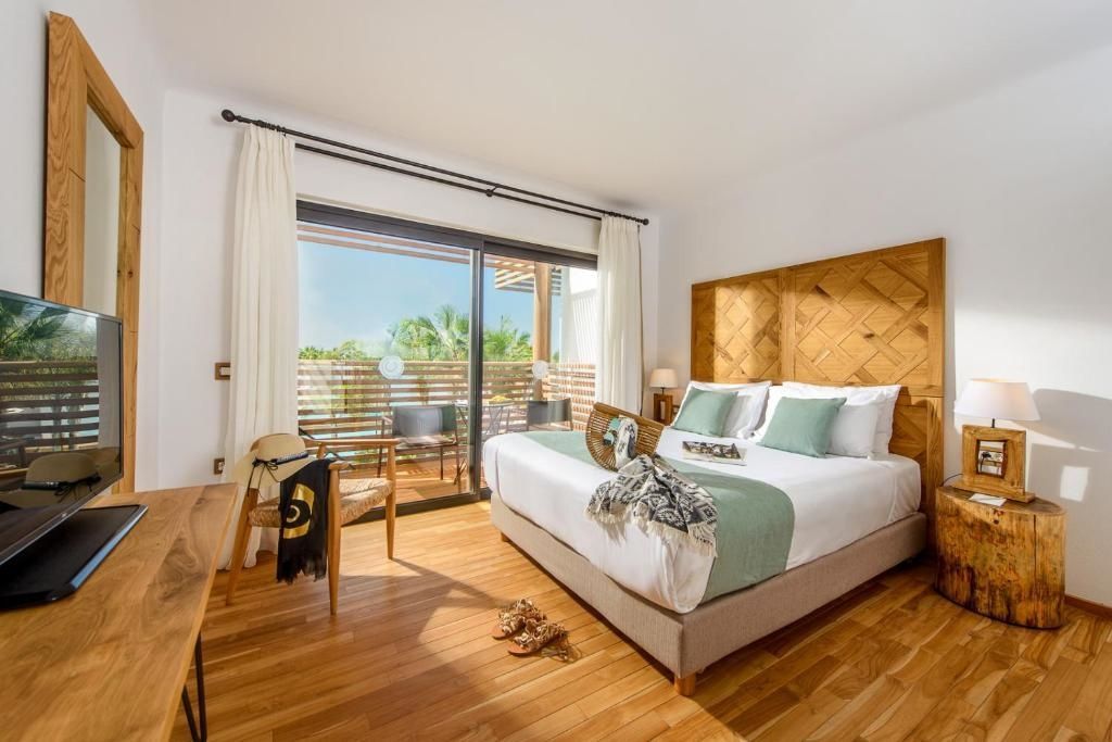 Doppelzimmer mit Holzpaneel hinter dem Bett und Schiebetür zur privaten Terrasse.