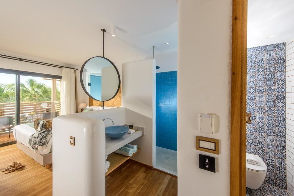 Badezimmerbereich mit blauem Waschbecken, rundem Spiegel und blau gefliester Dusche.