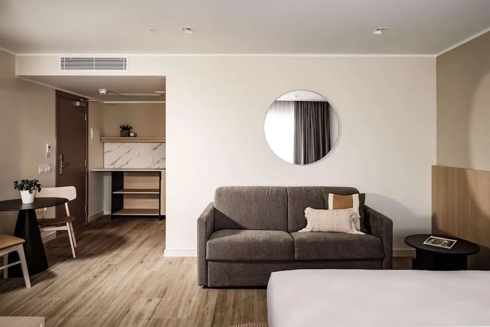 Schlafsofa an einer hellen Wand mit rundem Spiegel in einer modernen Suite.