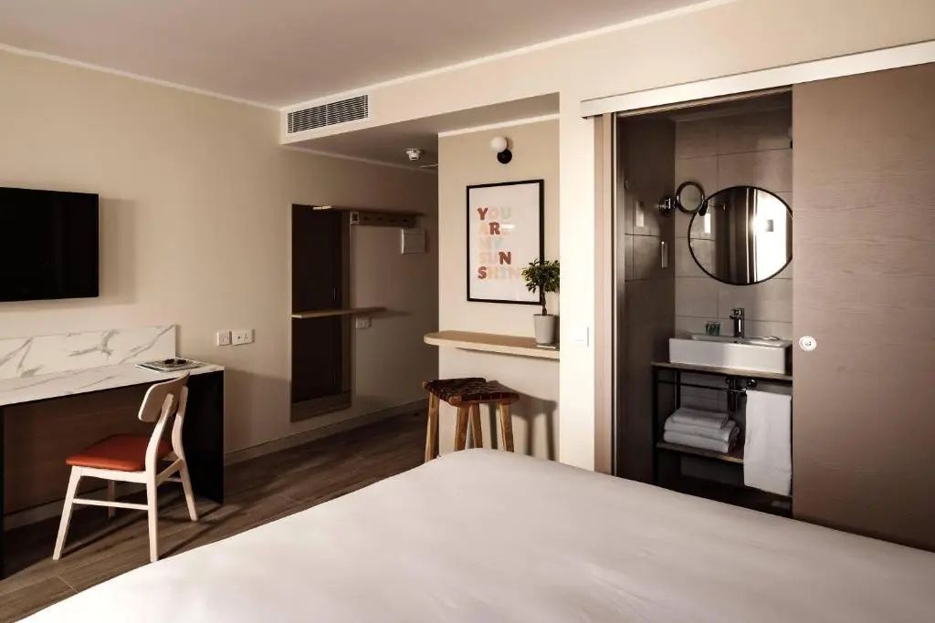 Blick in das Hotelzimmer mit Bett, Holzmöbeln und angrenzendem Bad