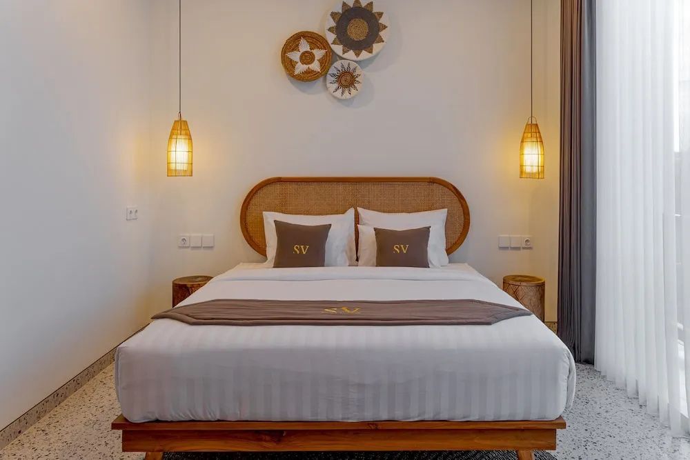 Doppelbett mit Flechtkopfteil, zwei Hängelampen und Wanddekoration aus Korb.