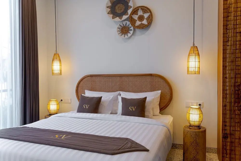 Doppelbett mit beleuchteten Nachttischlampen und Dekoration an der Wand.