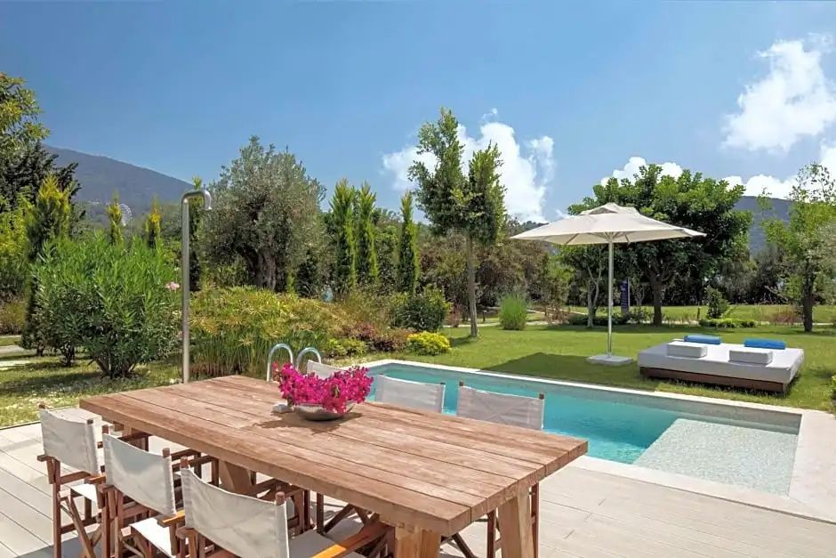 Private Terrasse mit Esstisch aus Holz, eigenem Pool und Blick in den grünen Garten.