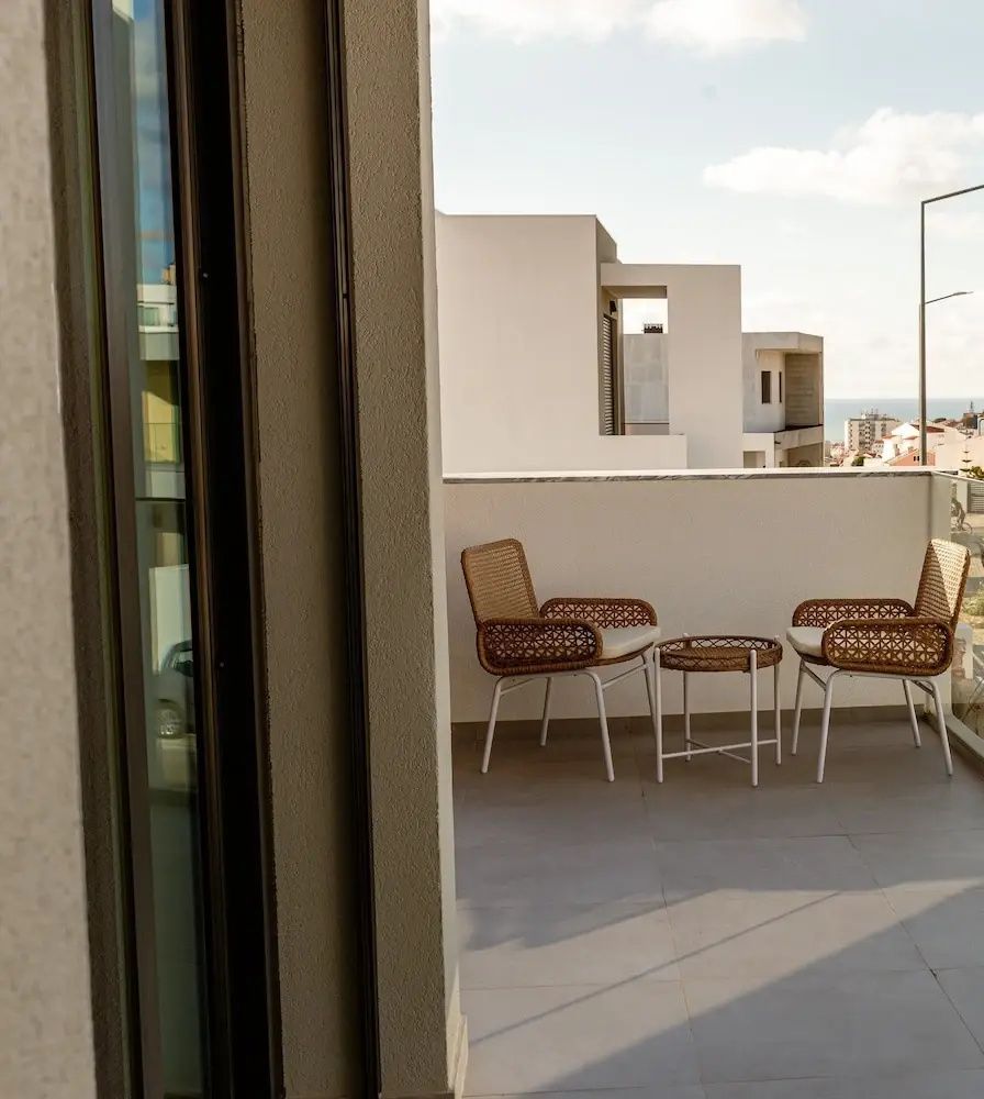 Balkon mit zwei Flechtsesseln und einem kleinen Tisch sowie Blick auf die Umgebung.