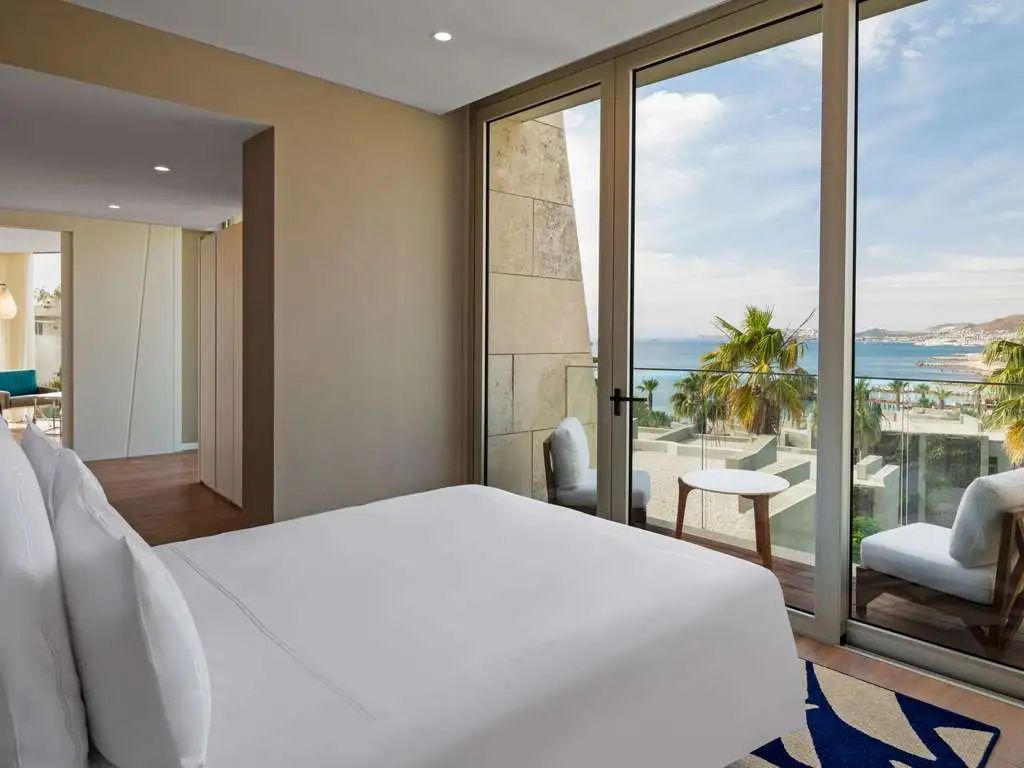 Modernes Doppelzimmer mit Parkettboden und Balkontür mit Aussicht auf das Meer.