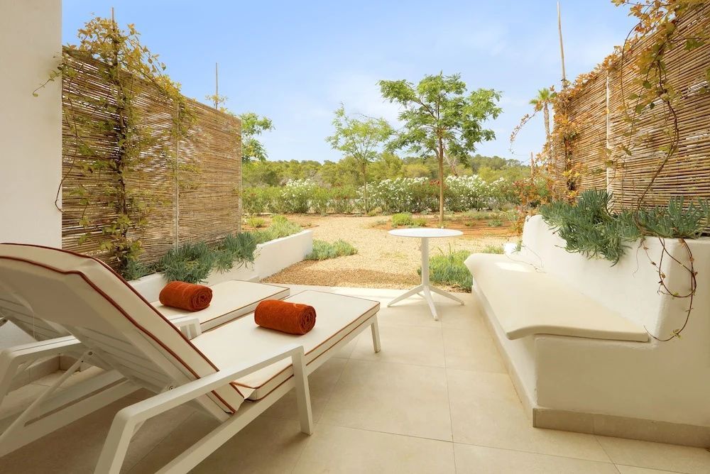 Terrasse mit zwei Sonnenliegen, orangefarbenen Handtüchern und Blick auf den Garten.