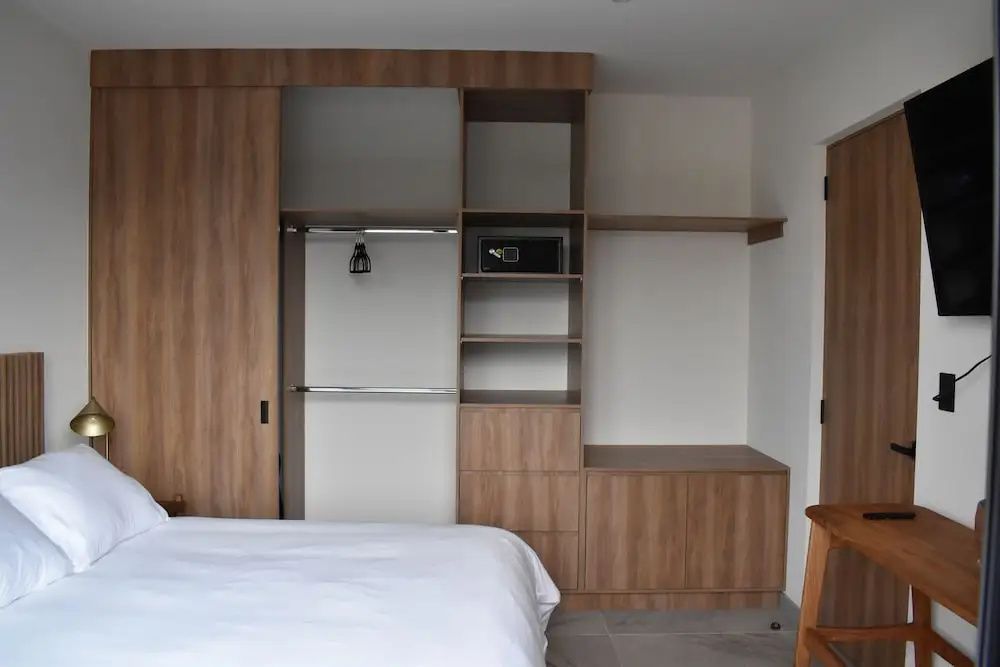 Offener Holzschrank mit integriertem Safe und Bett im Vordergrund.