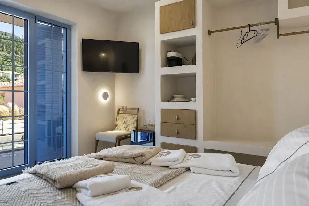 Modernes Hotelzimmer mit bezogenem Bett, Wandfernseher und Regal aus Holz.