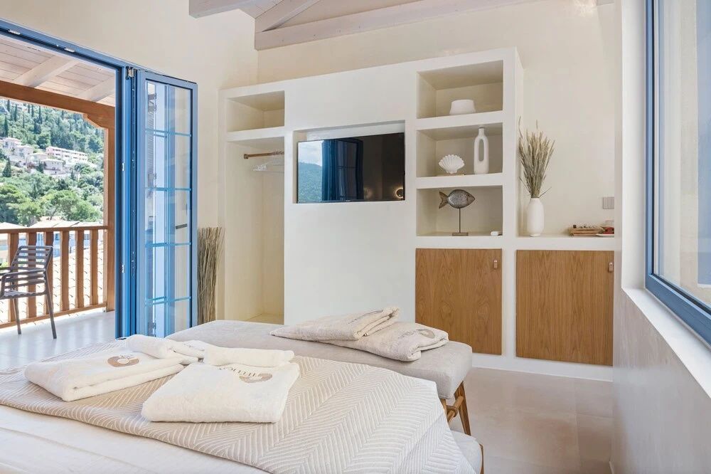 Weißer Einbauschrank mit Fernseher und Regalfächern im hellen Hotelzimmer.