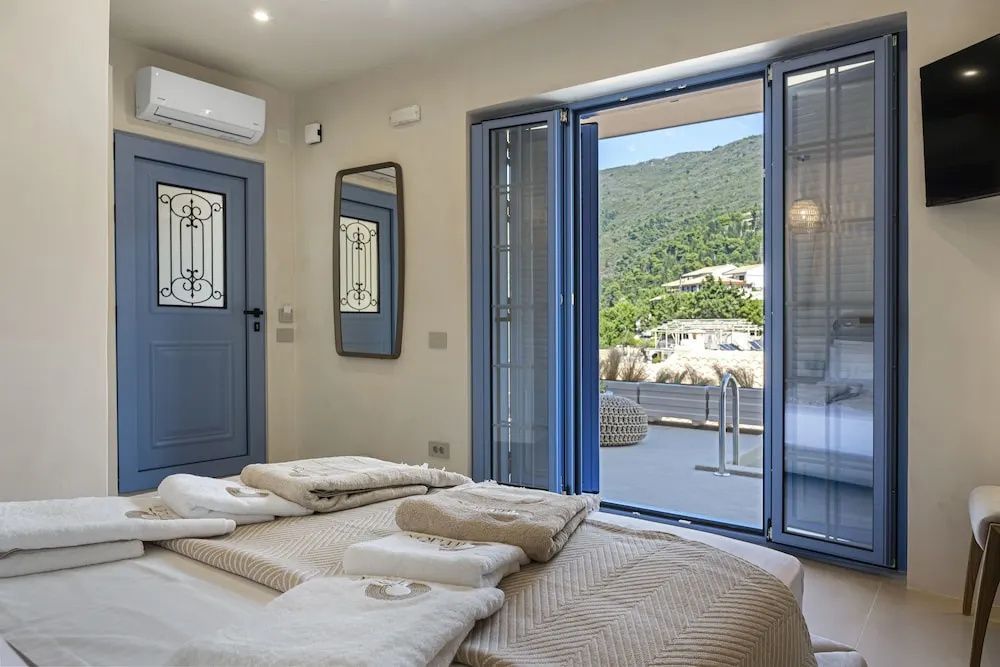 Blick aus dem Schlafzimmer durch die geöffnete blaue Tür auf die Terrasse und Berge.