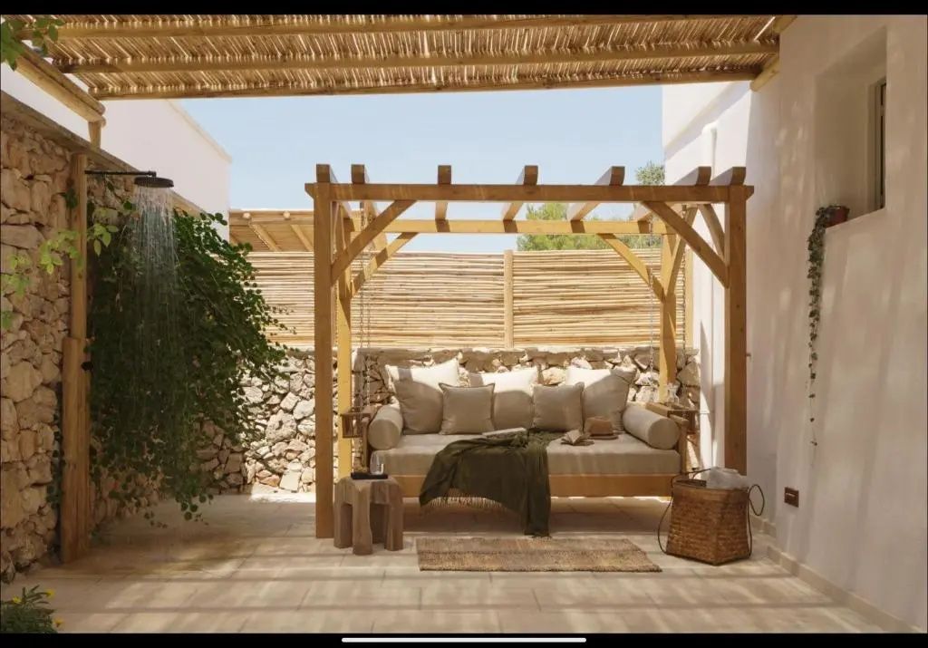 Überdachte Terrasse mit großem Schaukelbett aus Holz und vielen Kissen.