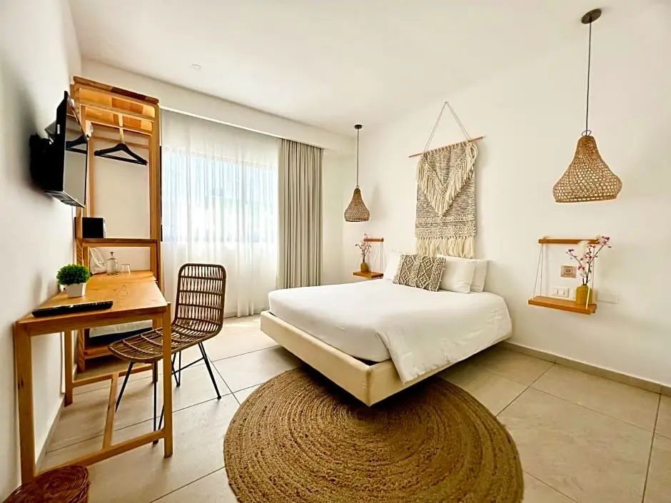 Hell eingerichtetes Hotelzimmer mit Doppelbett, Teppich und Holzschreibtisch.