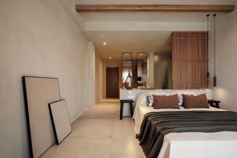 Geräumige Suite mit großem Doppelbett, hellem Fliesenboden und Holzdeckenbalken.