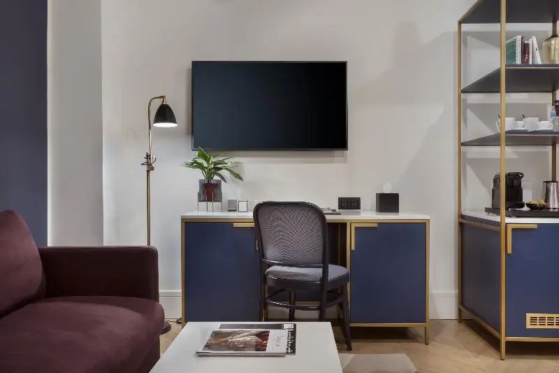Schreibtisch im Hotelzimmer mit blauem Kommodenschrank, Flachbildfernseher und Stehlampe