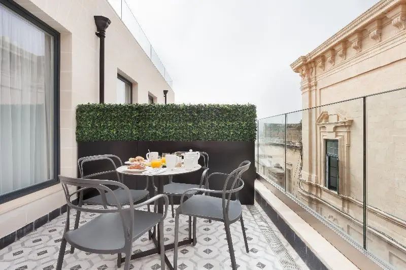 Dachterrasse mit Tisch, Stühlen und Blick auf umliegende Gebäude.