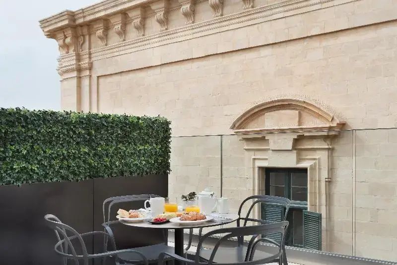 Gedeckter Tisch auf einer Terrasse vor einer historischen Sandsteinwand.
