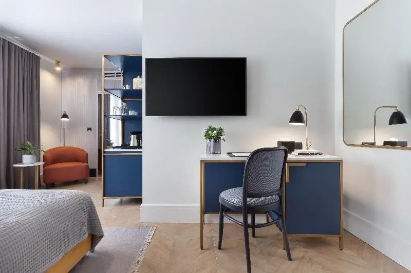 Schreibtisch mit blauem Stuhl und Fernseher an der Wand im Hotelzimmer.