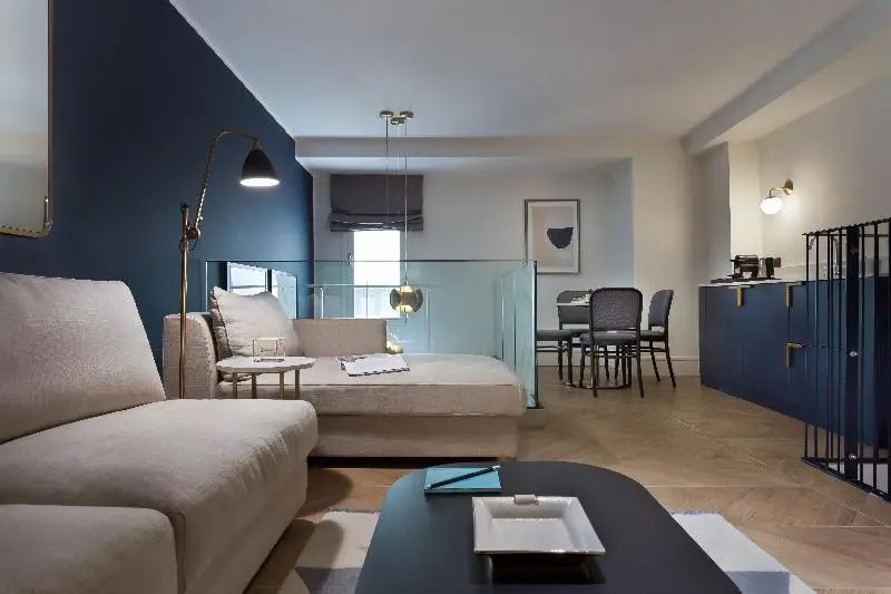Wohnbereich einer Suite mit hellem Ecksofa, Couchtisch und kleiner Sitzgruppe.