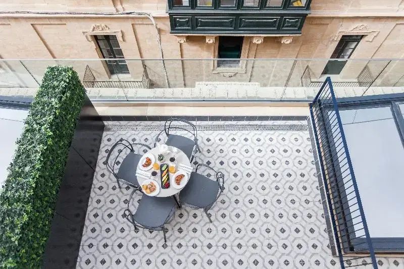 Terrasse mit gemustertem Fliesenboden, rundem Tisch, Stühlen und Glasgeländer.