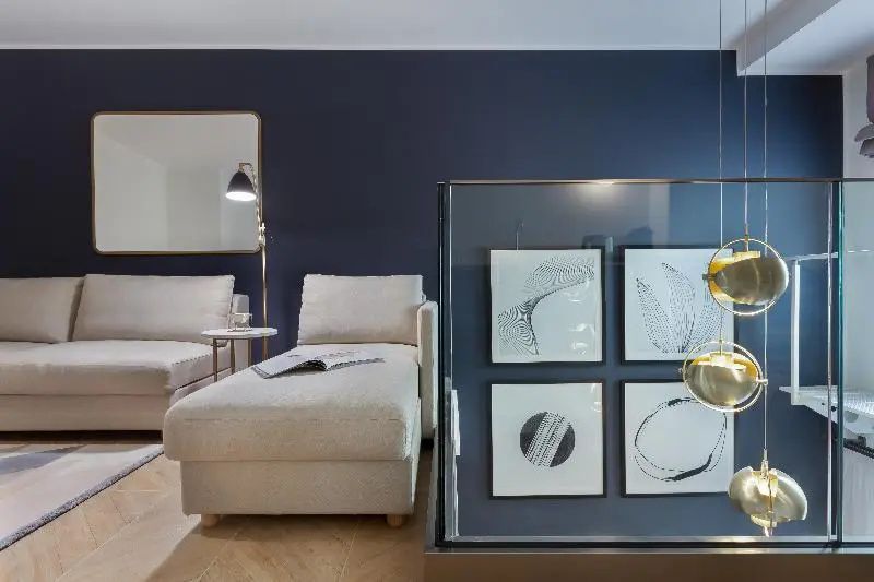 Moderner Sitzbereich im Hotelzimmer mit beigen Chaiselongues und dunkelblauer Wand.