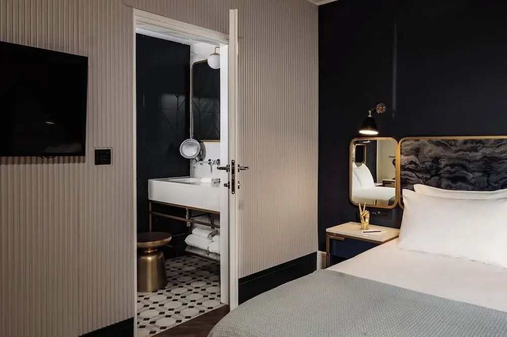 Blick aus dem Hotelzimmer auf das angrenzende Badezimmer mit hellem Waschtisch.