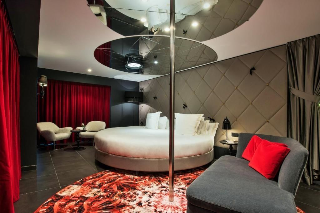 Rundes Bett in dunkel gestaltetem Zimmer mit Tanzstange und Deckenspiegel.