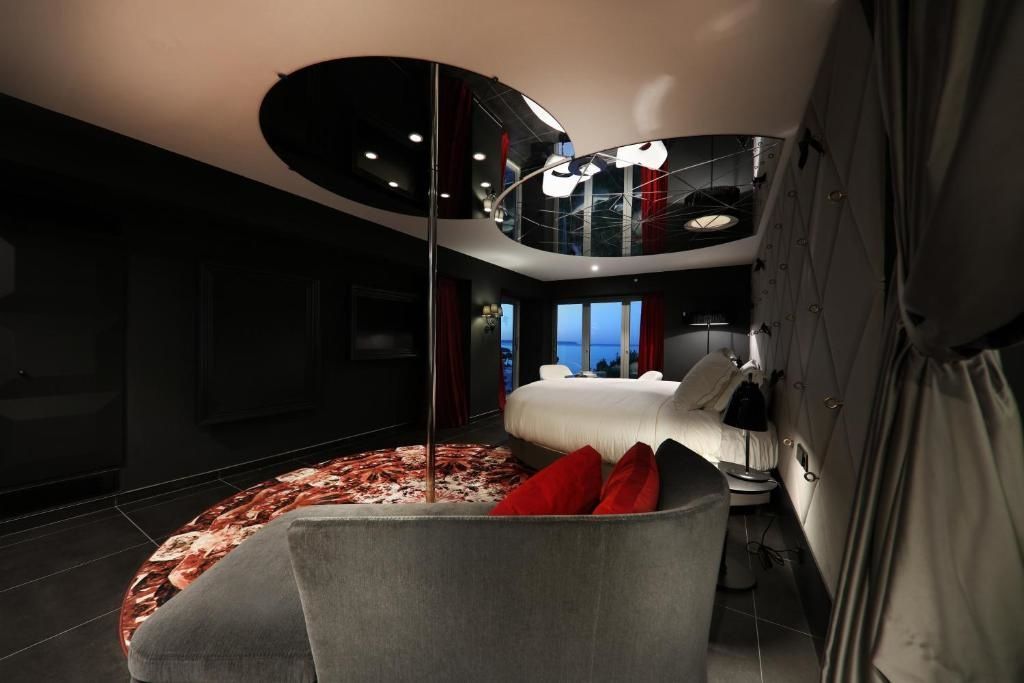 Geräumige Suite mit rundem Bett, Stange, Chaiselongue und Blick aufs Meer.