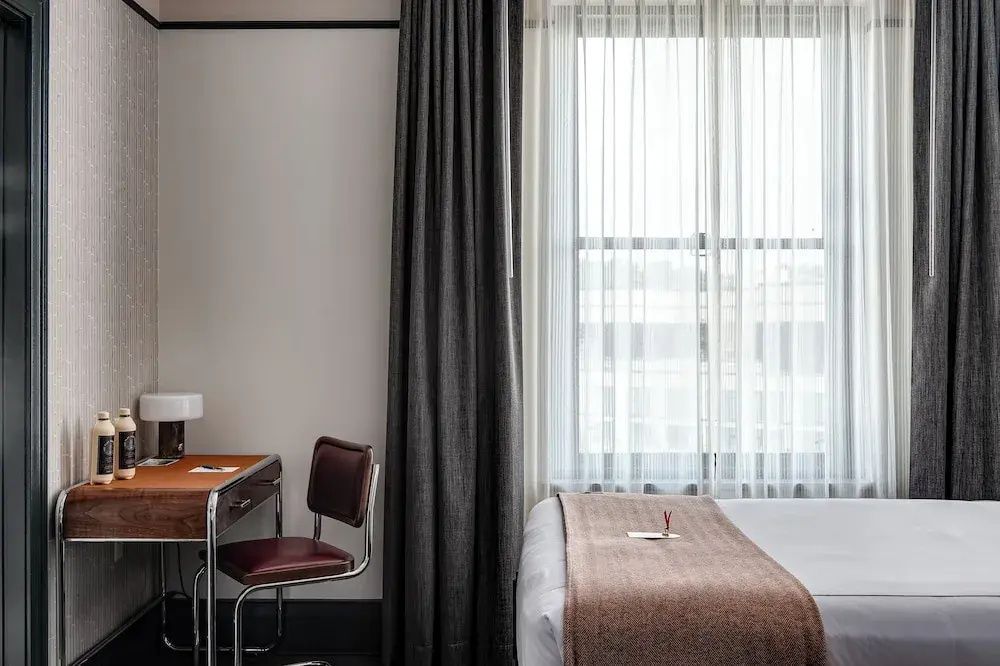 Arbeitsbereich mit Holzschreibtisch, Lederstuhl und Fenster im Hotelzimmer.