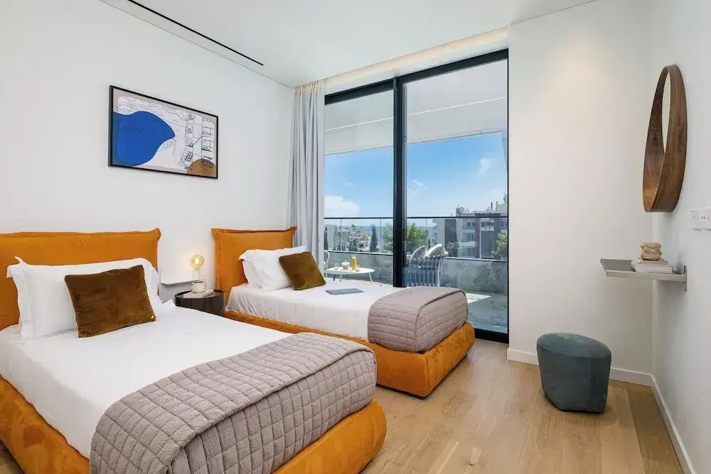 Schlafzimmer mit zwei Einzelbetten, Holzfußboden und Blick auf den Balkon.