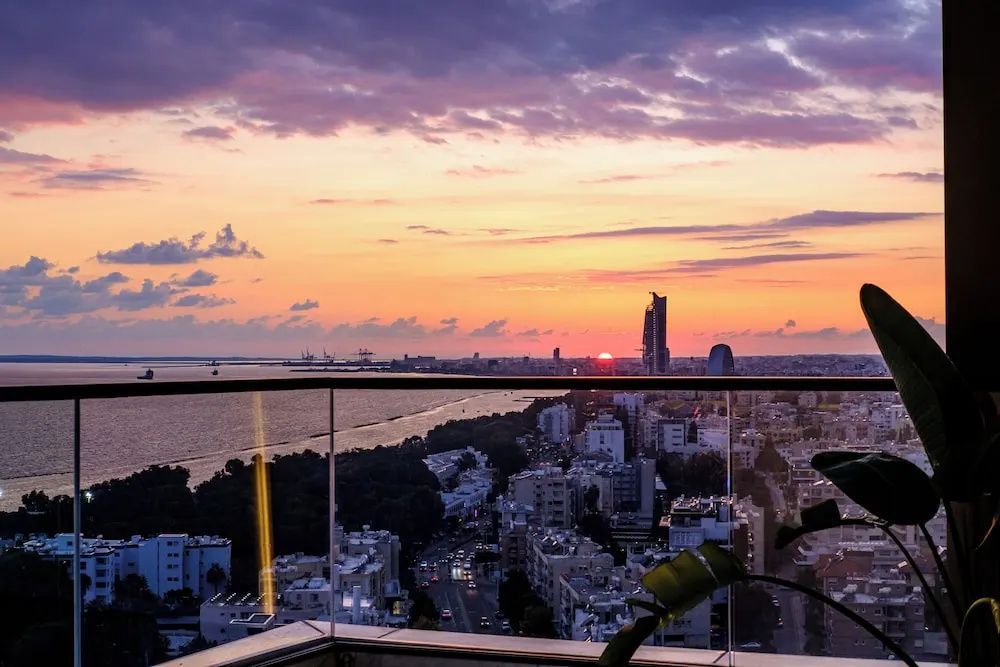 Blick vom Balkon bei Sonnenuntergang über die Küstenstadt und das Meer.