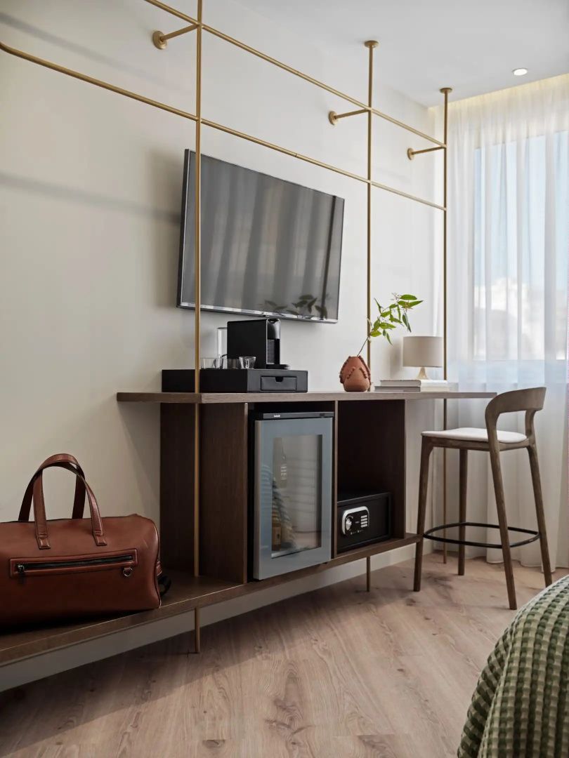 Schreibtischbereich im Hotelzimmer mit Flachbild-TV, Minibar, Tresor und Sitzgelegenheit.