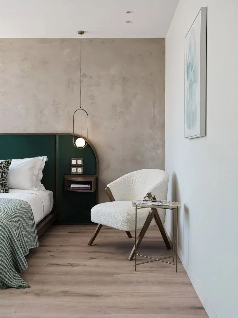Heller Sitzbereich im Zimmer mit weißem Sessel, Beistelltisch und Wandbild.
