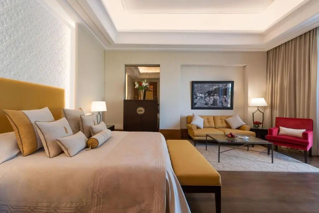 Schlafbereich mit großem Doppelbett, gelbem Sofa und Couchtisch in einer Suite.